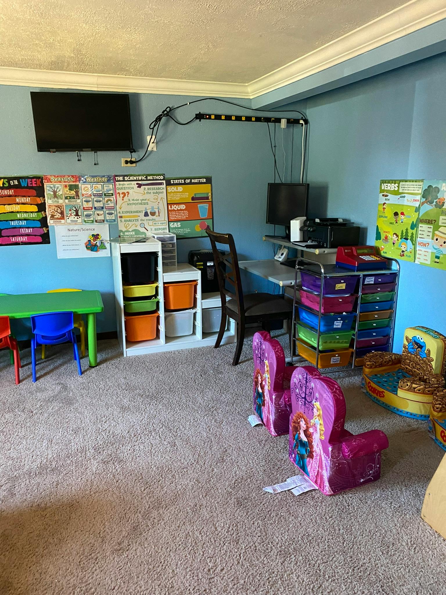 Room with a small green table and chairs, storage units, and wall decorations