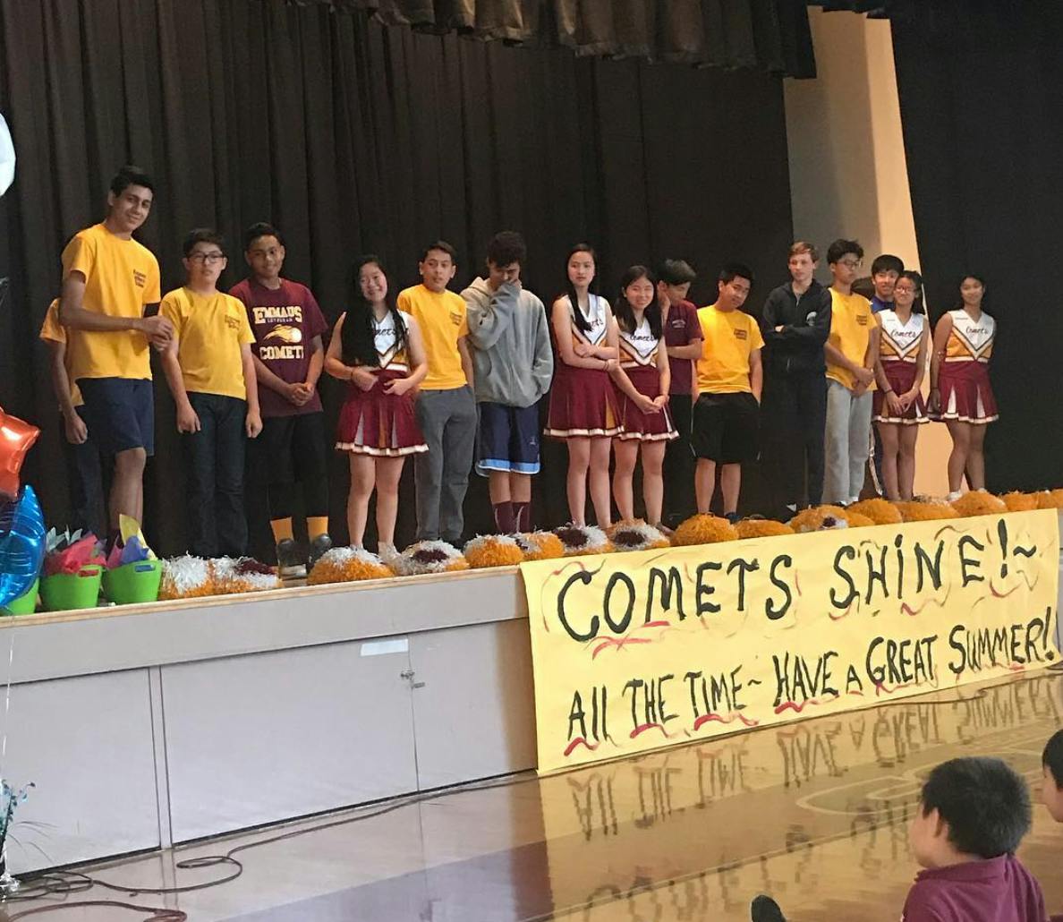 Teens and children standing on a stage with a banner that reads "COMETS SHINE!"