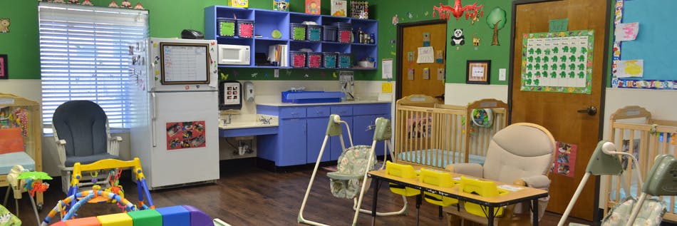Daycare room with cribs, changing station, and play equipment