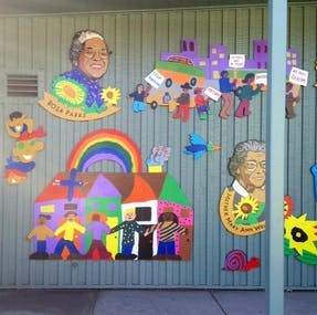 Mural with colorful cutouts of people, houses, and a rainbow