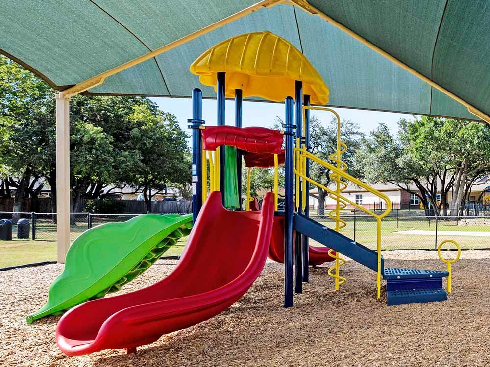 Colorful playground structure with slides under a green shade canopy