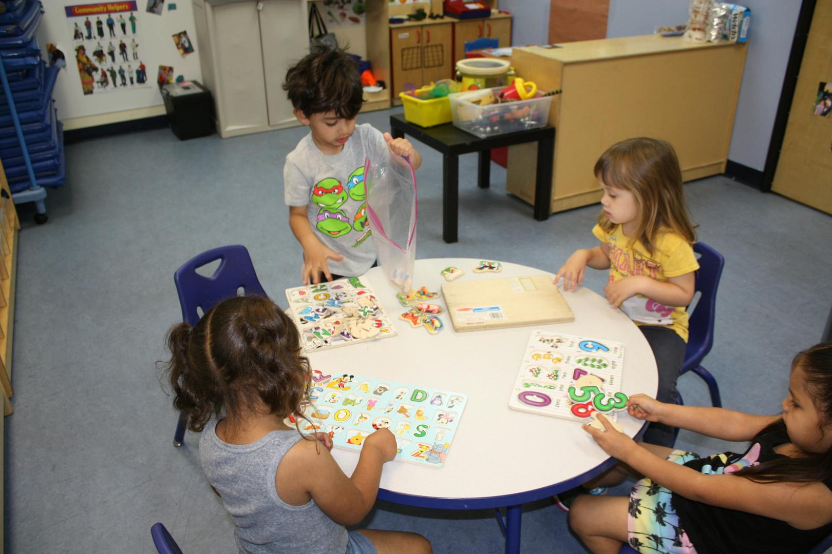 Children playing with puzzles and learning materials at a table in a classroom