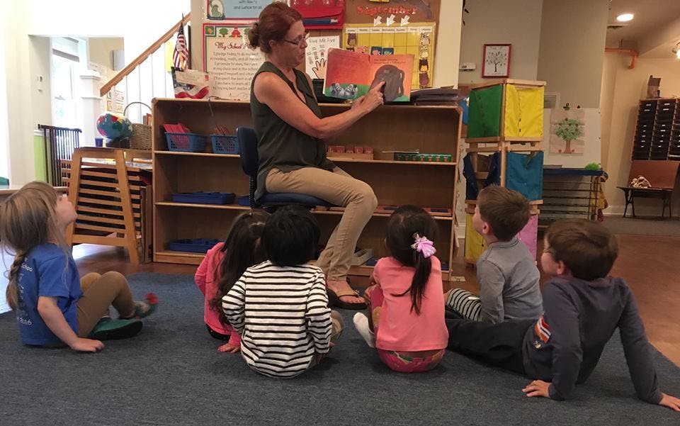 Person reading a book to children in a classroom