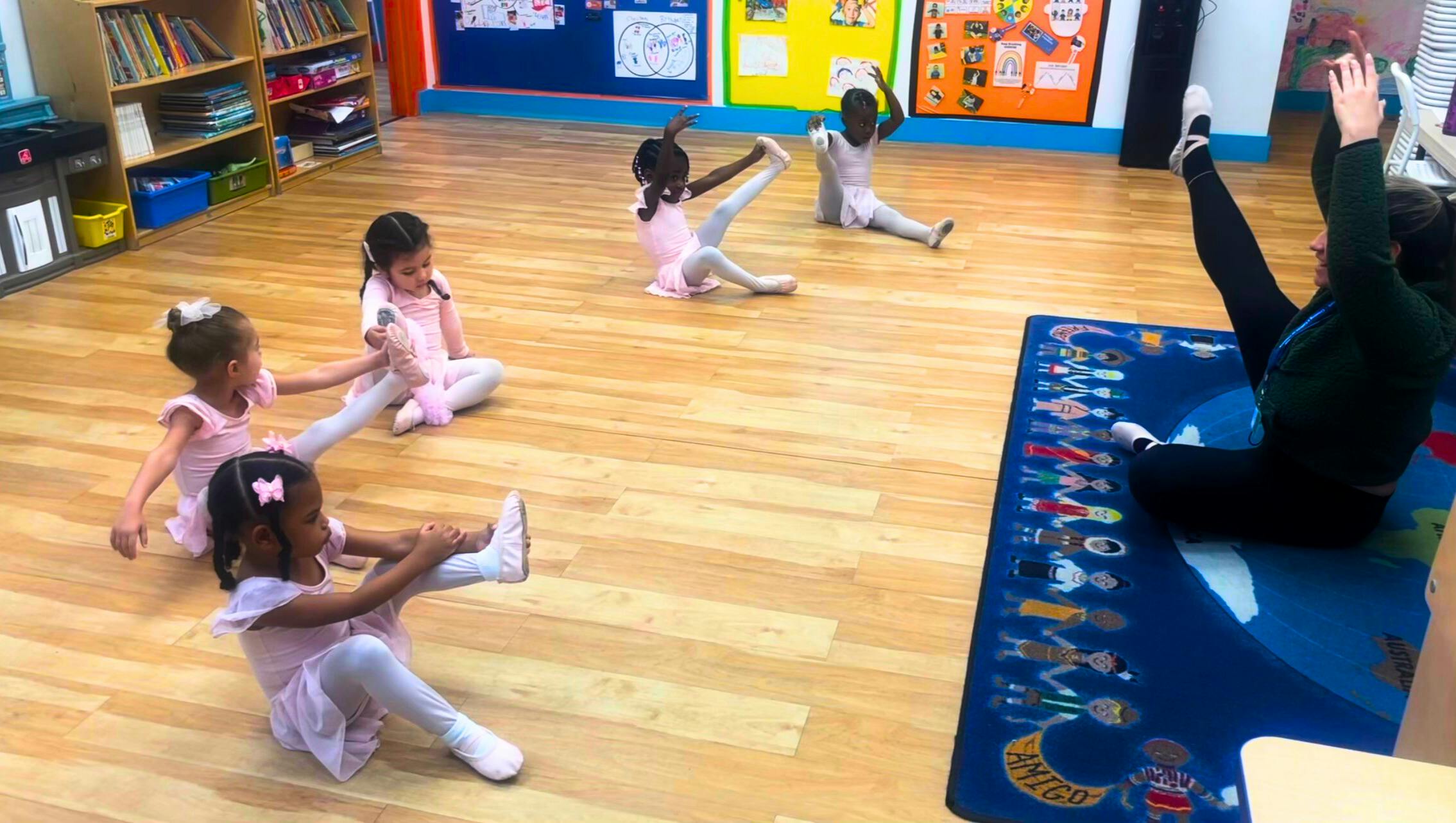 Children and an adult stretching on a wooden floor