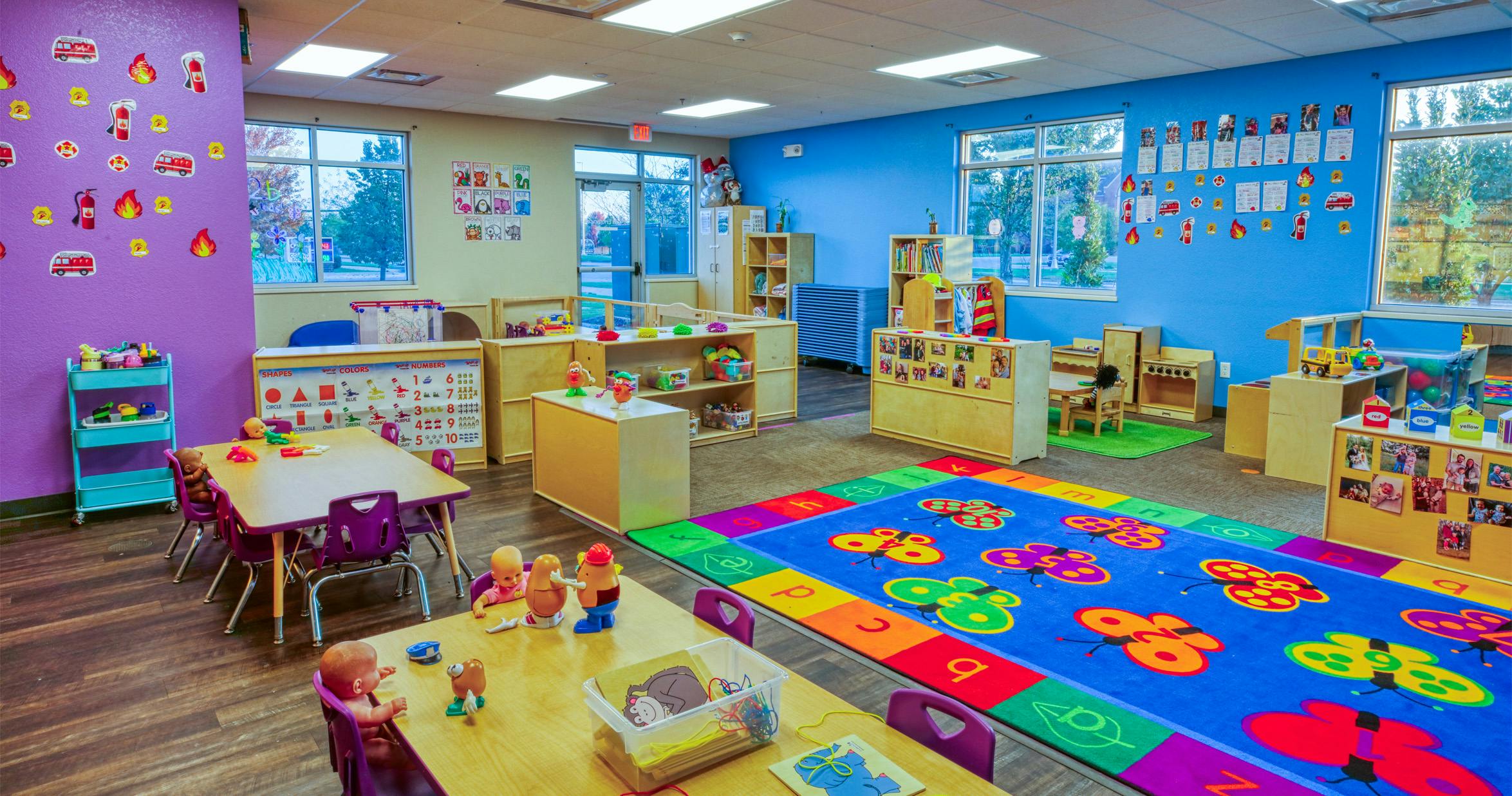 Colorful preschool classroom with tables, chairs, and learning materials