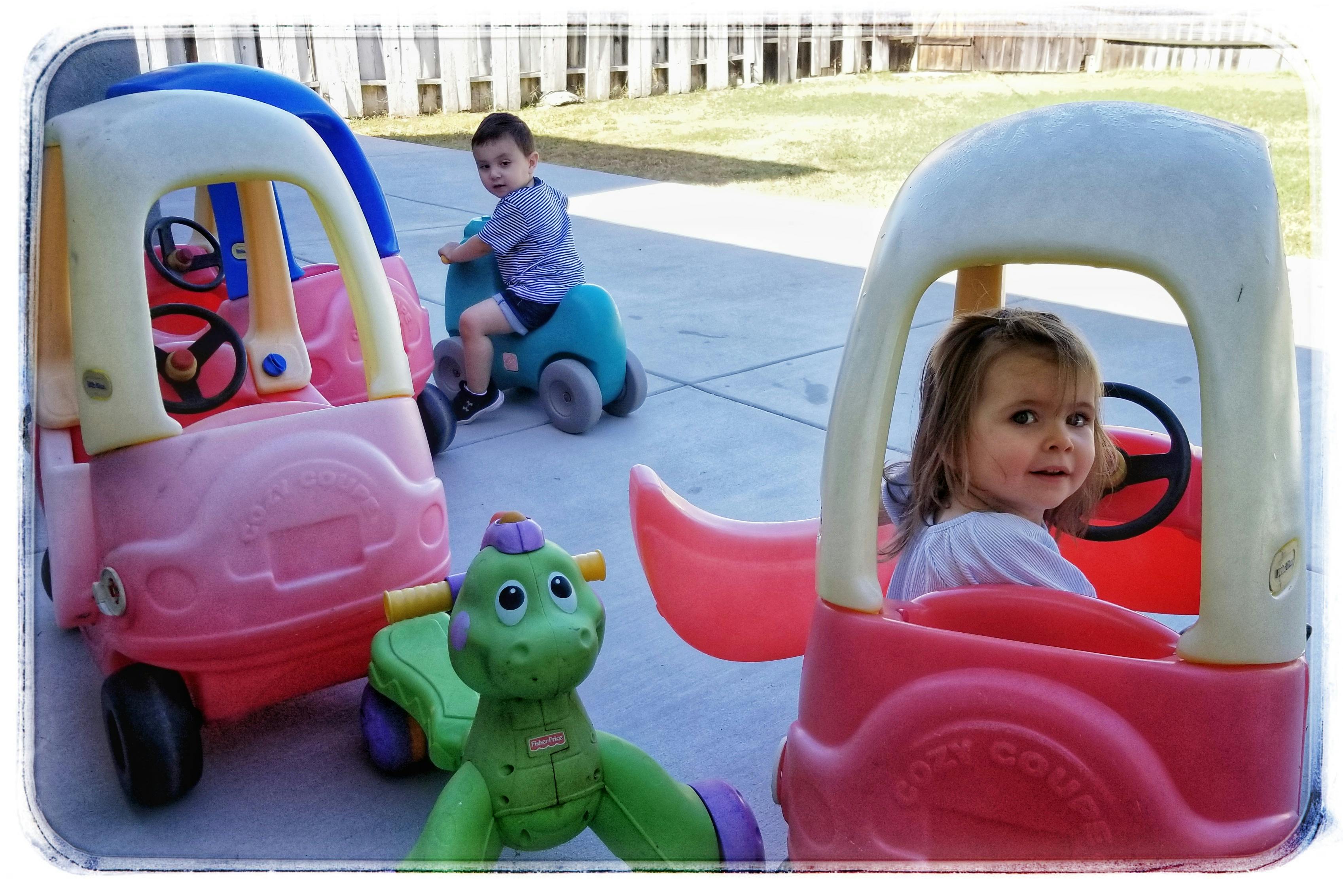 Two children playing with toy cars outdoors