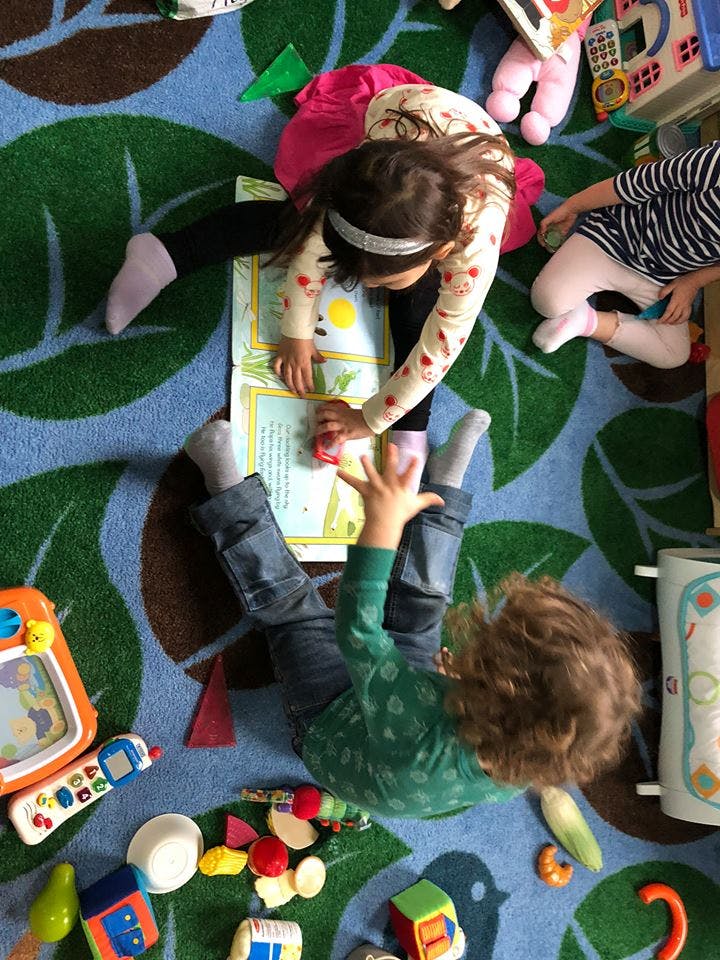 Two children on a patterned rug looking at a book