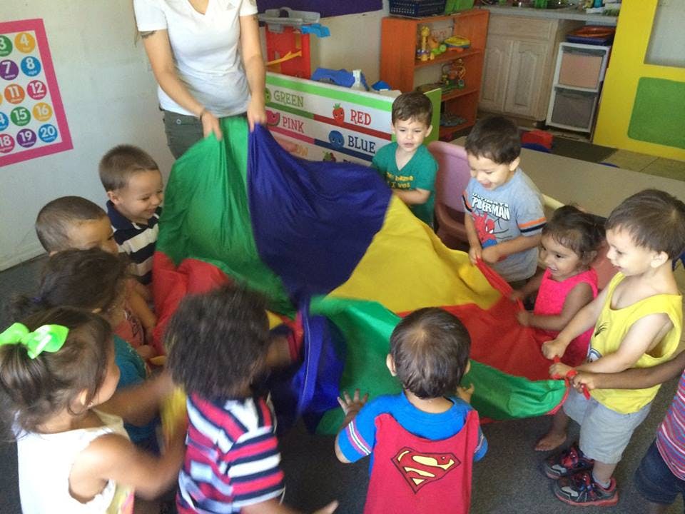 Adult and children playing with a colorful parachute