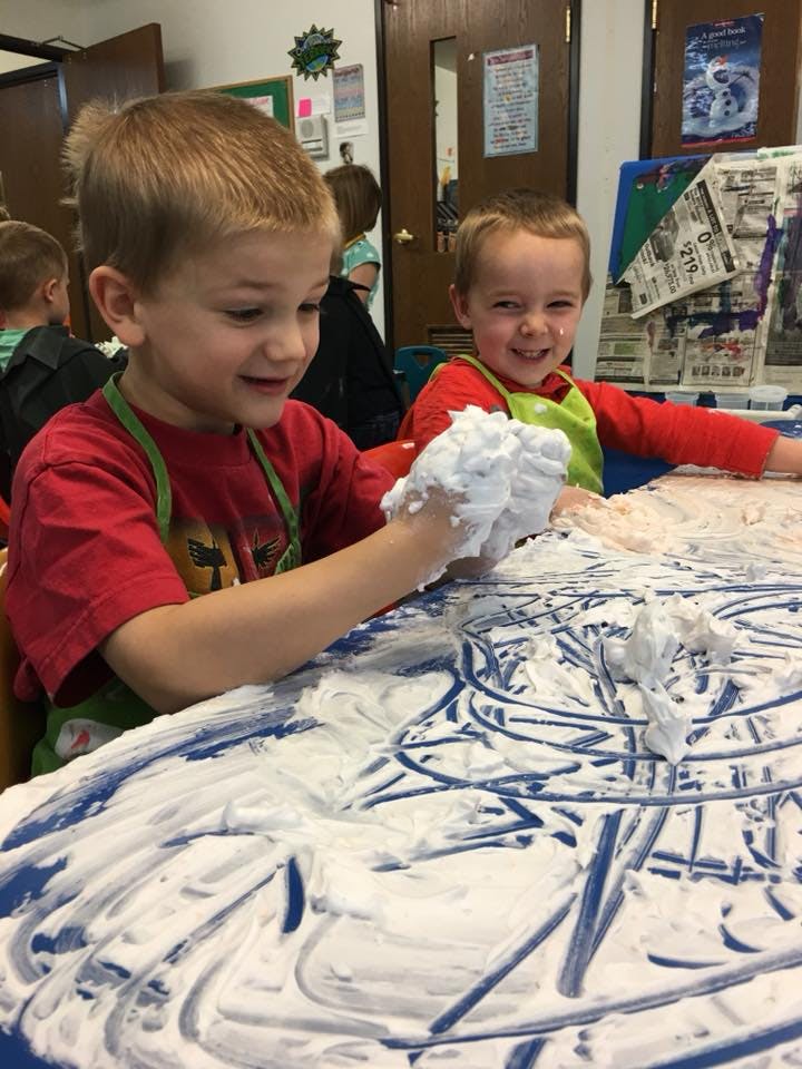 Two children playing with shaving cream on a table