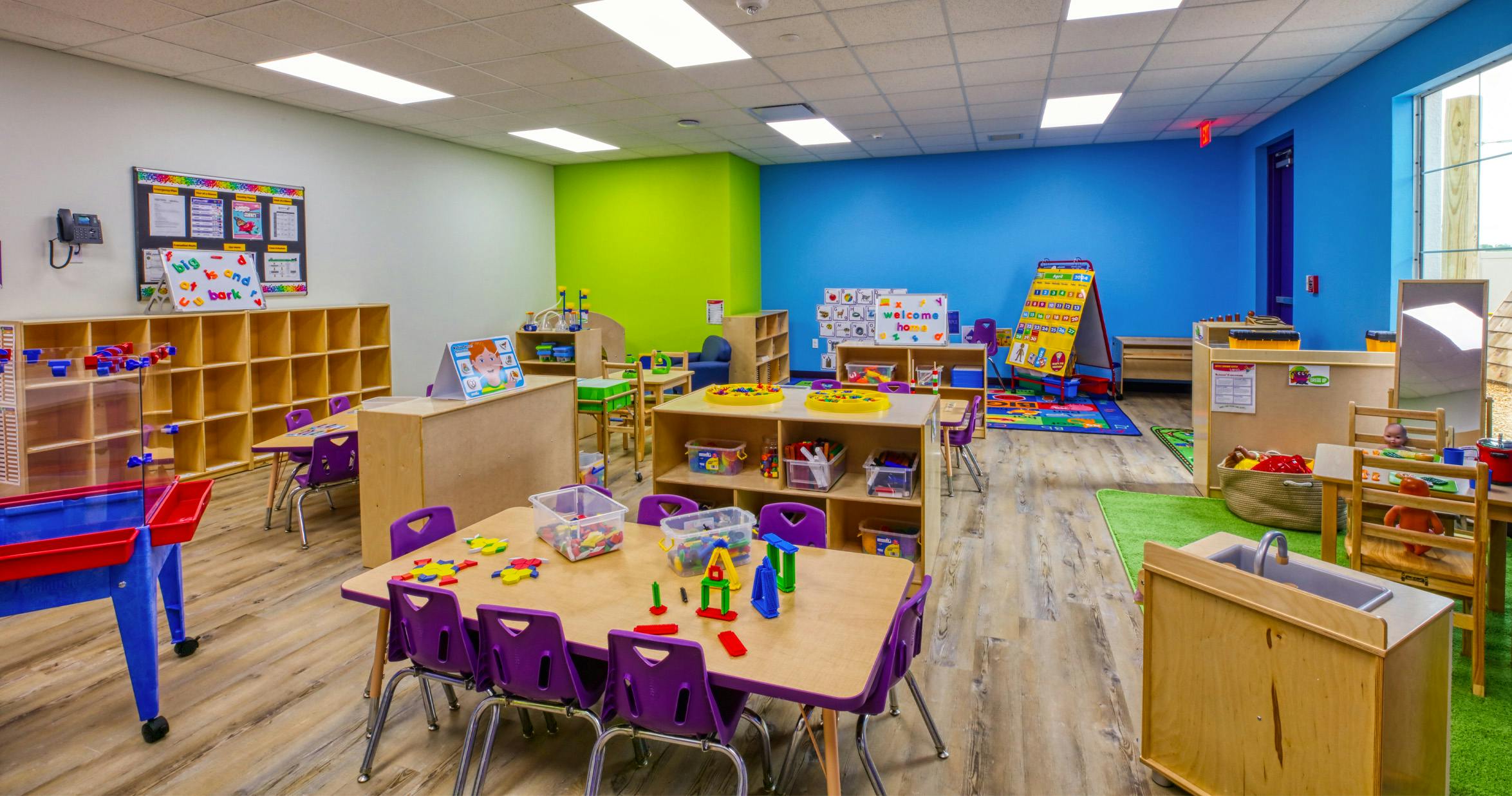 Classroom with child-sized tables and chairs, toys, and learning materials