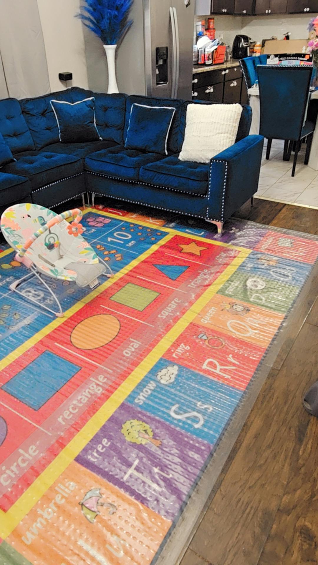 Baby bouncer on a colorful playmat in a living room