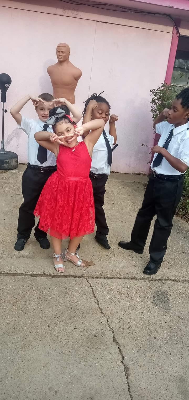 Four children posing with a punching dummy in the background