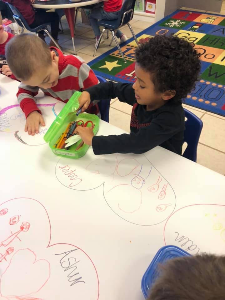 Two children drawing at a table in a classroom