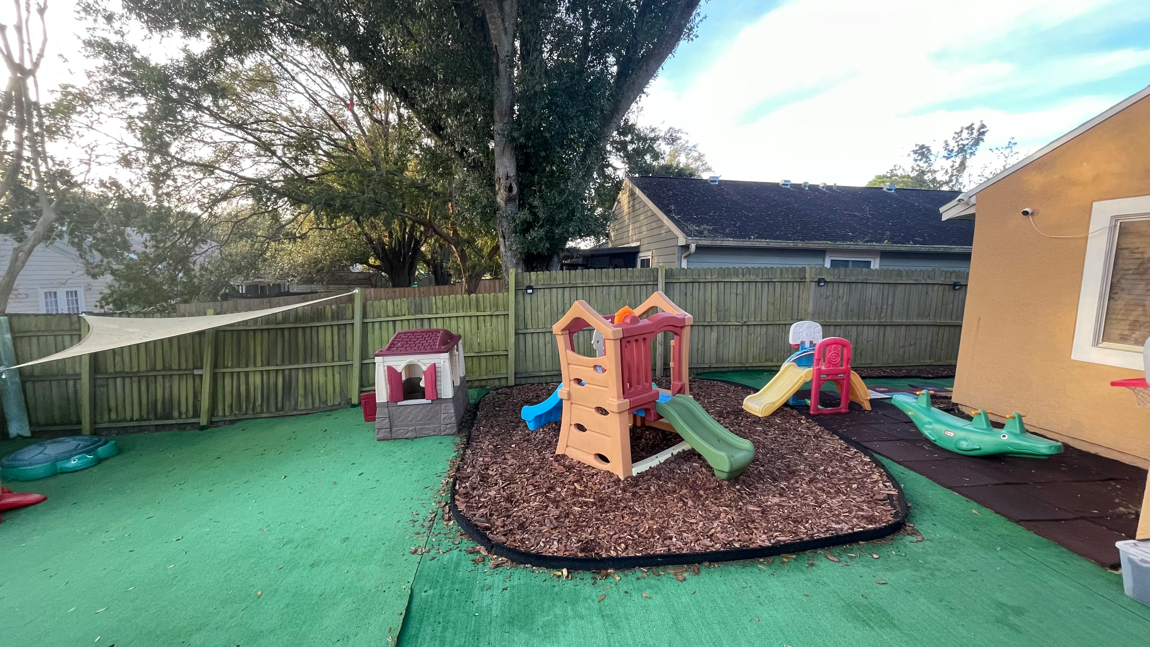 Outdoor playground with slides and play structures on wood chips and green turf