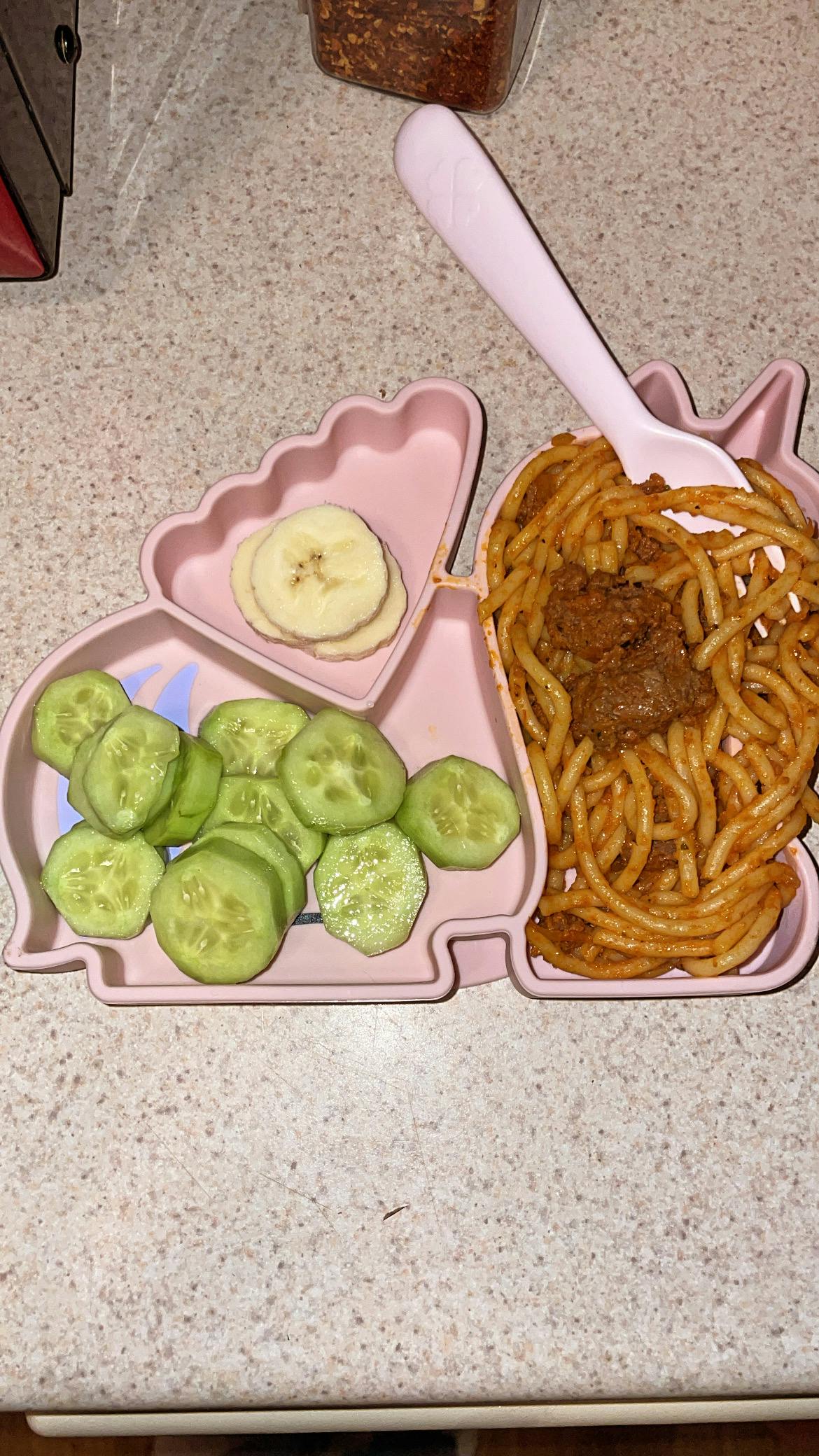 Child's plate with spaghetti and meat, sliced cucumbers, and banana