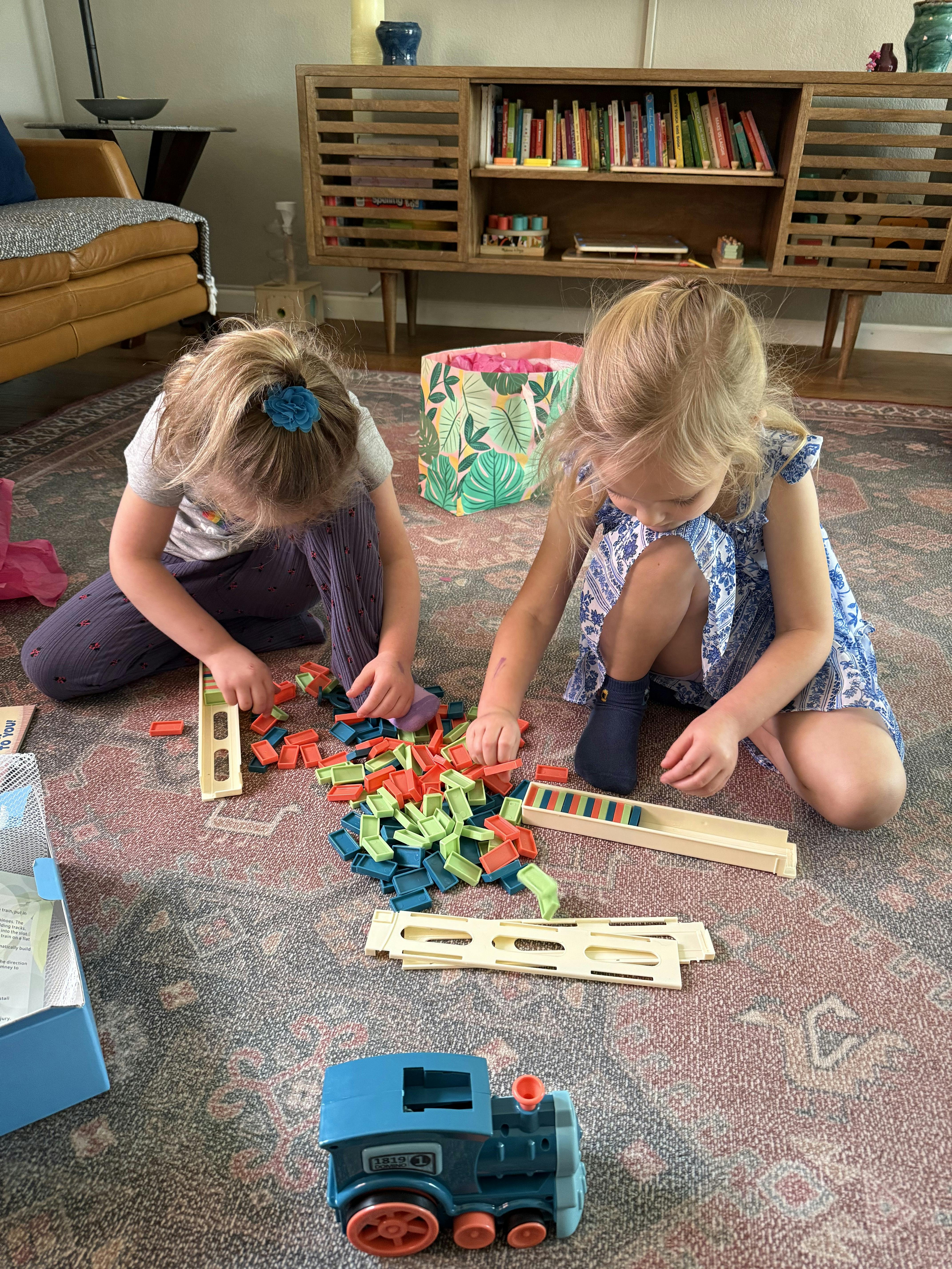 Two children playing with dominoes on a rug