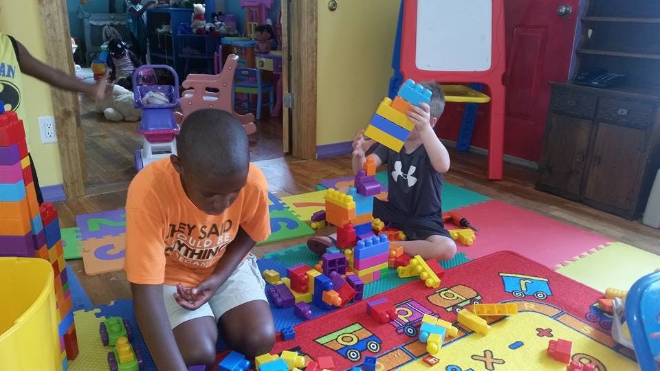 Two children playing with colorful building blocks on a mat
