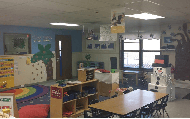 An empty classroom with desks, shelves, and a large paper snowman