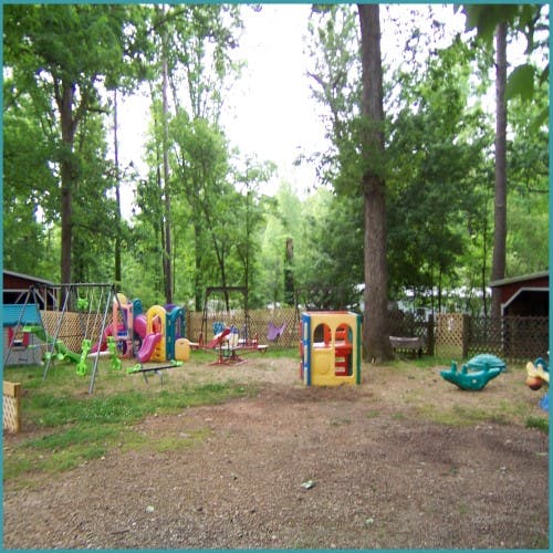 Playground with swings, slides, and climbing structures in a wooded area