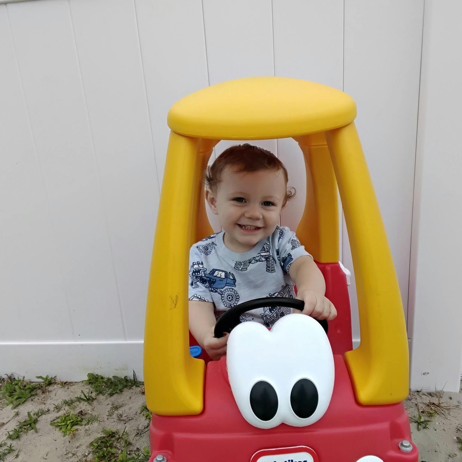 Child smiling while sitting in a toy car