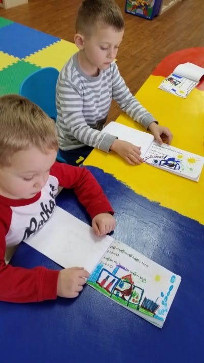 Two children looking at books at a table