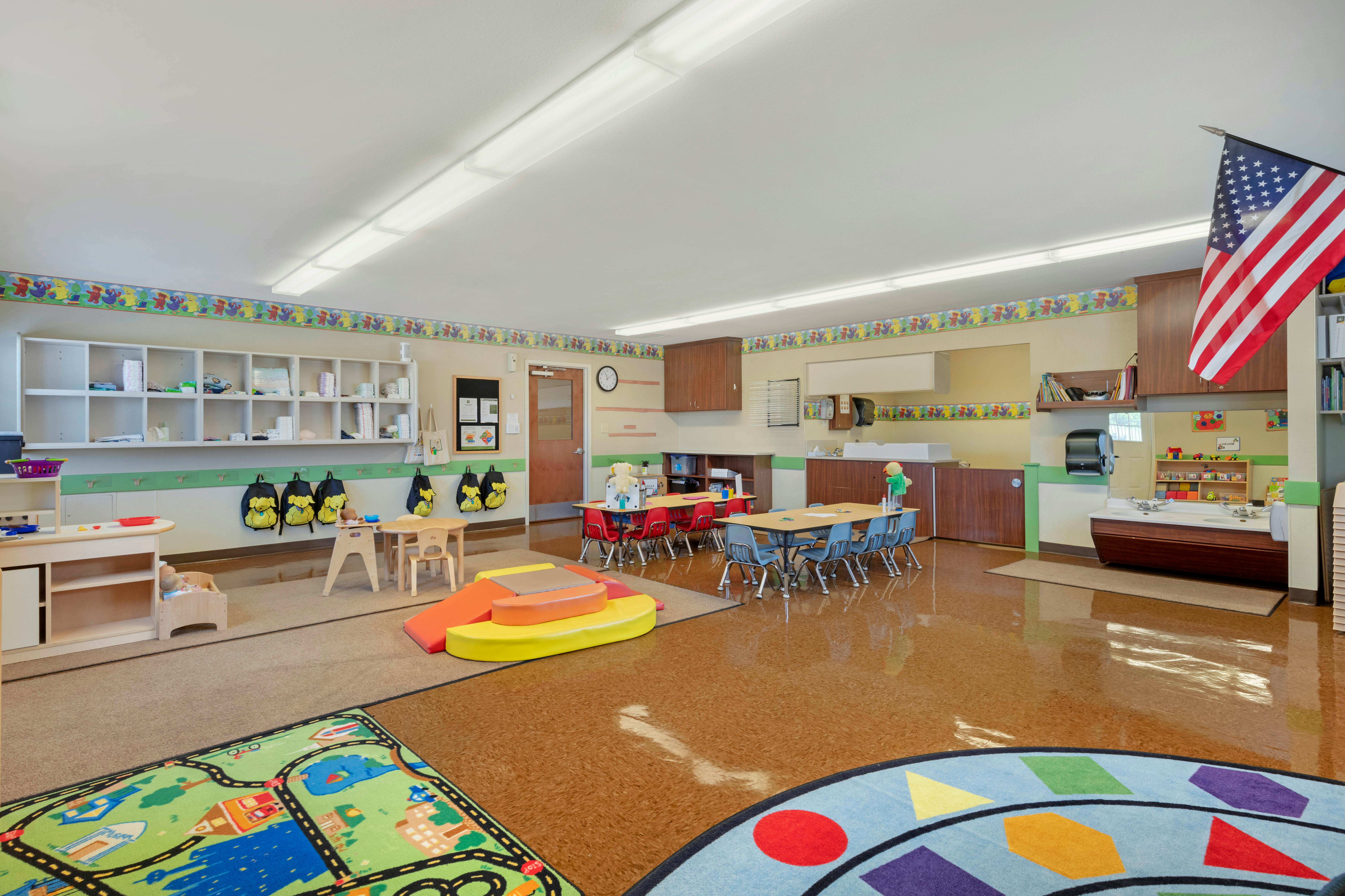 Classroom with play areas, small tables, and sinks