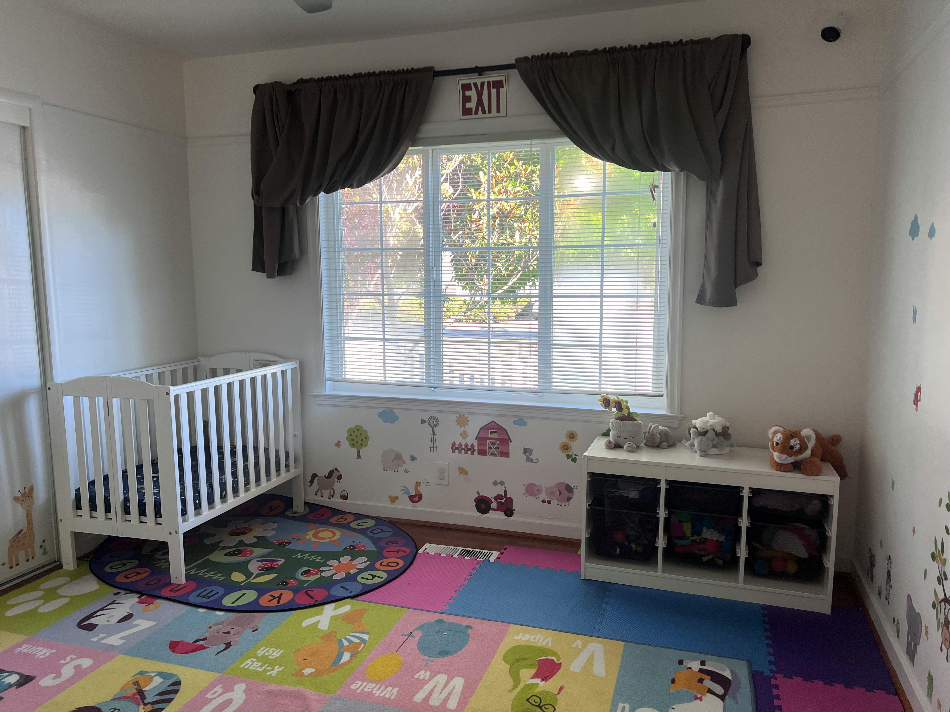Nursery room with a white crib, window, and play mats
