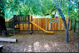 playground with a wooden structure and yellow slide