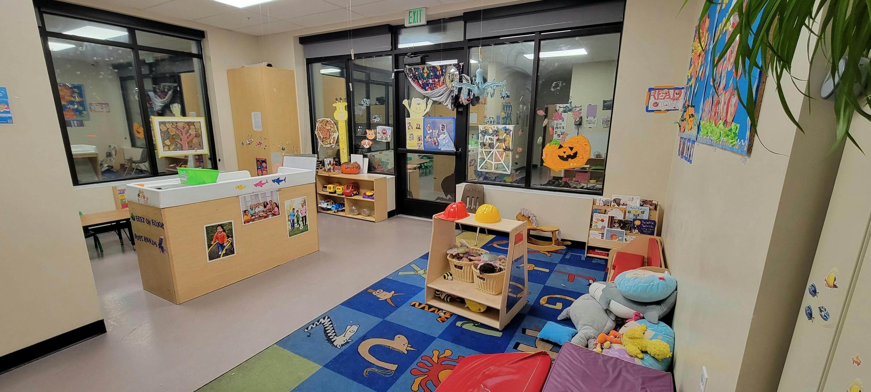 Playroom with a blue rug, toys, and windows