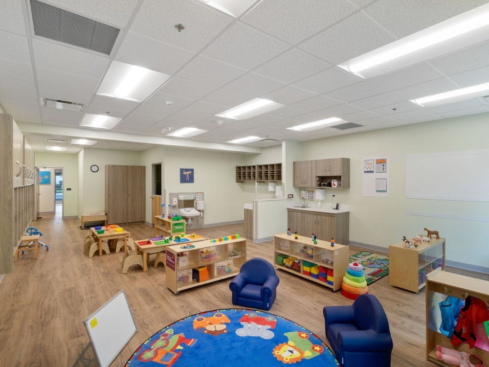 Empty classroom with small tables, chairs, and shelves with toys
