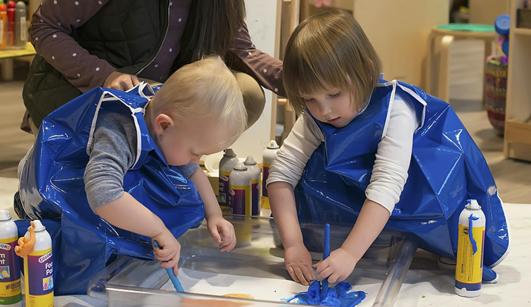 Two children in blue smocks painting