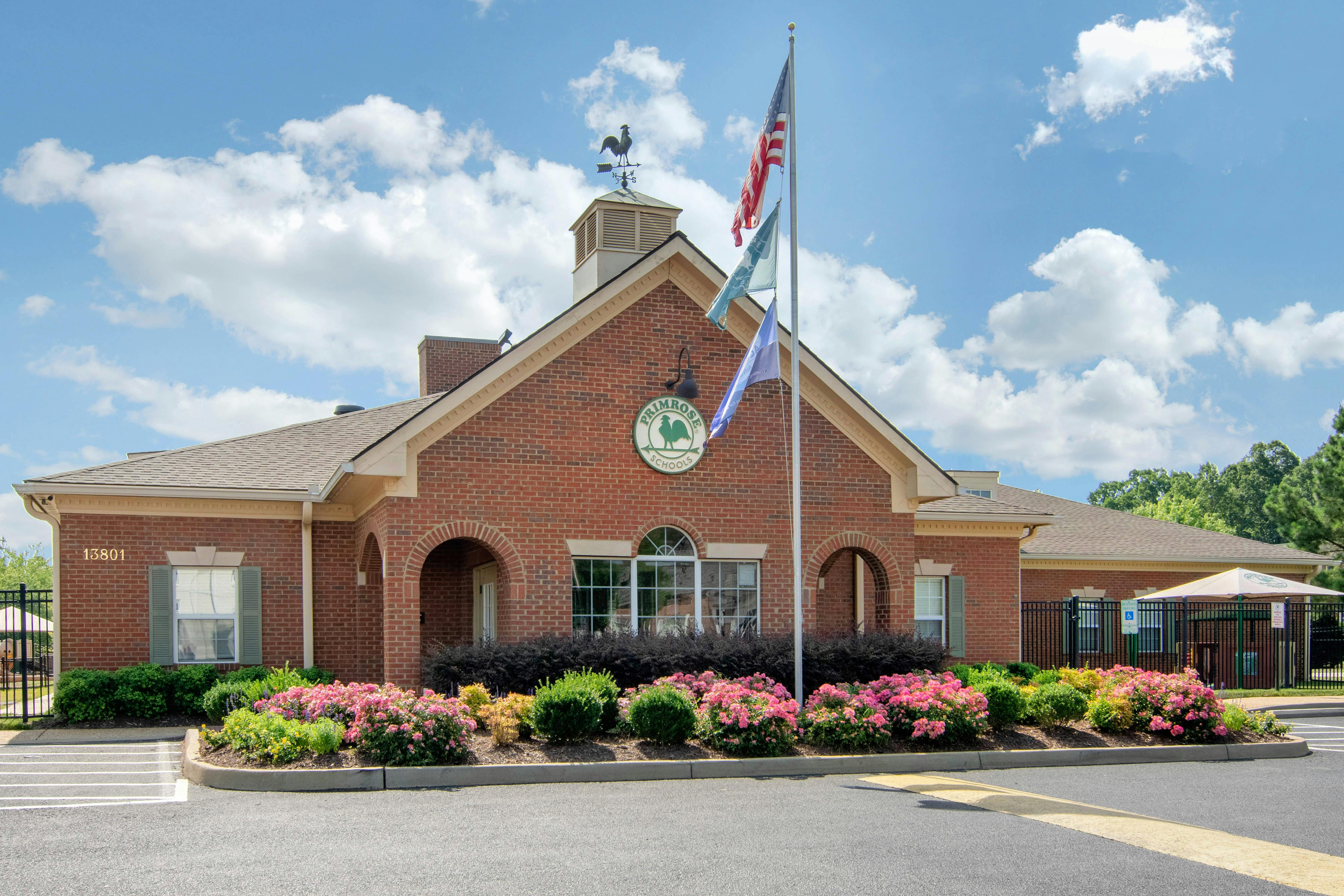 Brick building with a weather vane, flagpole, and Primrose Schools sign