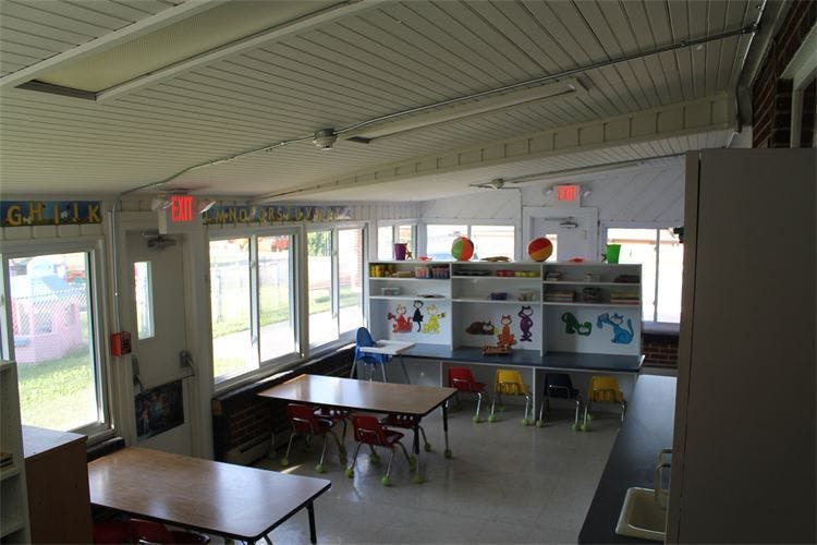 Classroom with tables, chairs, and shelves with art supplies