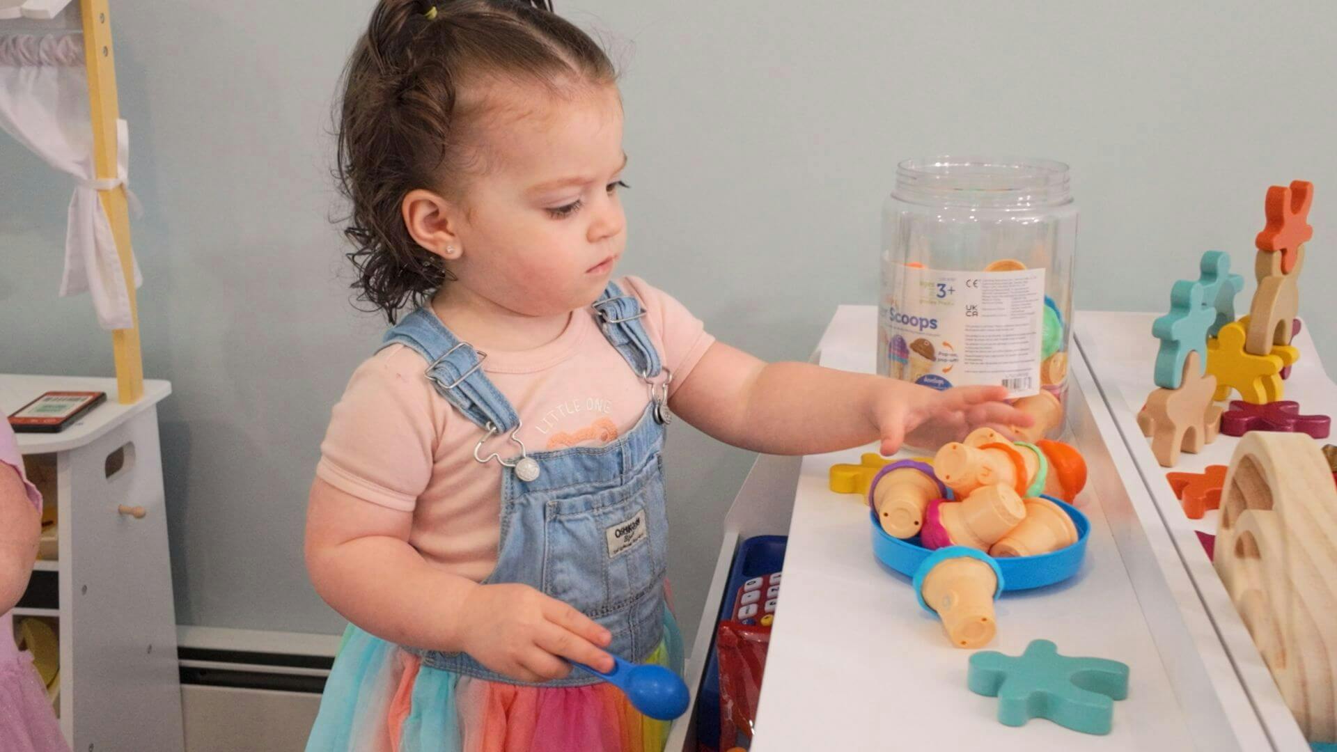 Child playing with a toy ice cream set on a table