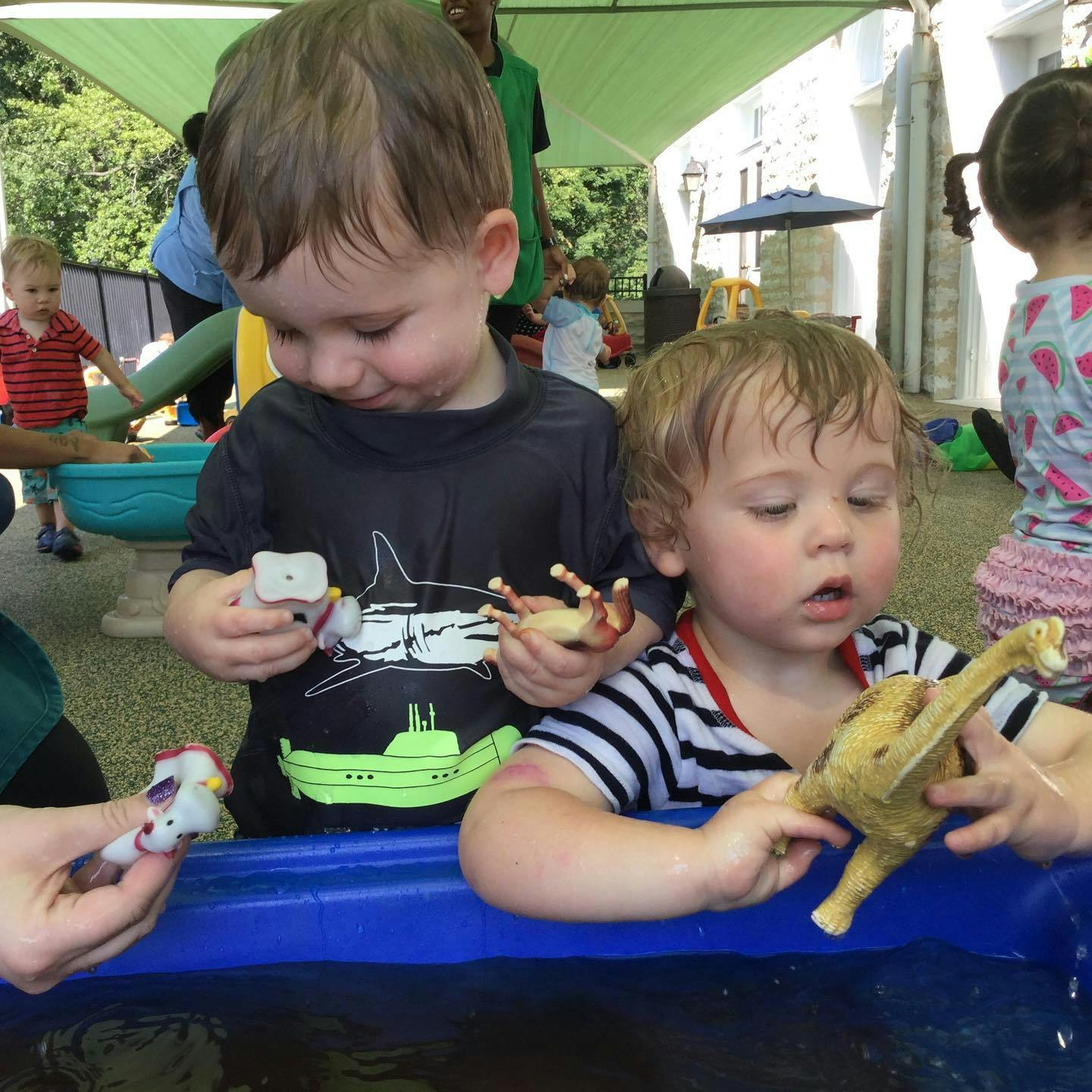 Two children playing with toys in a water table