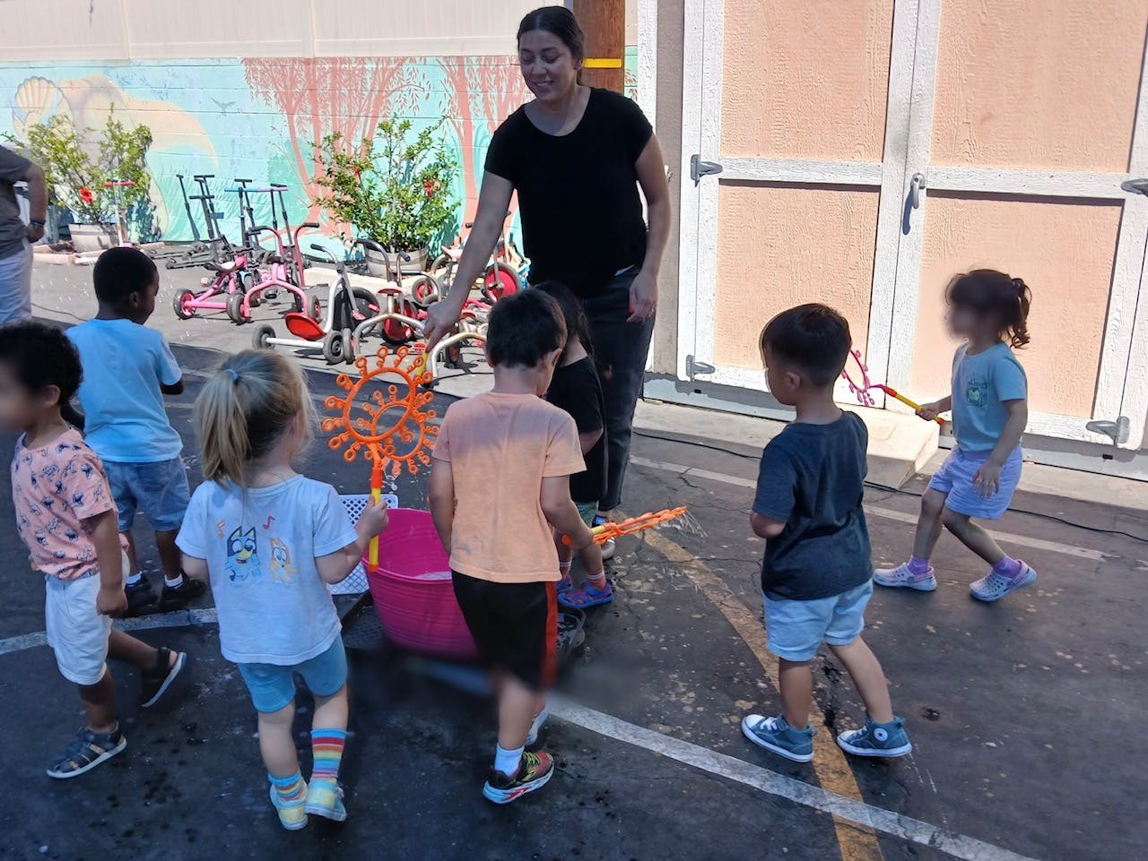Adult and several children playing with bubbles outdoors