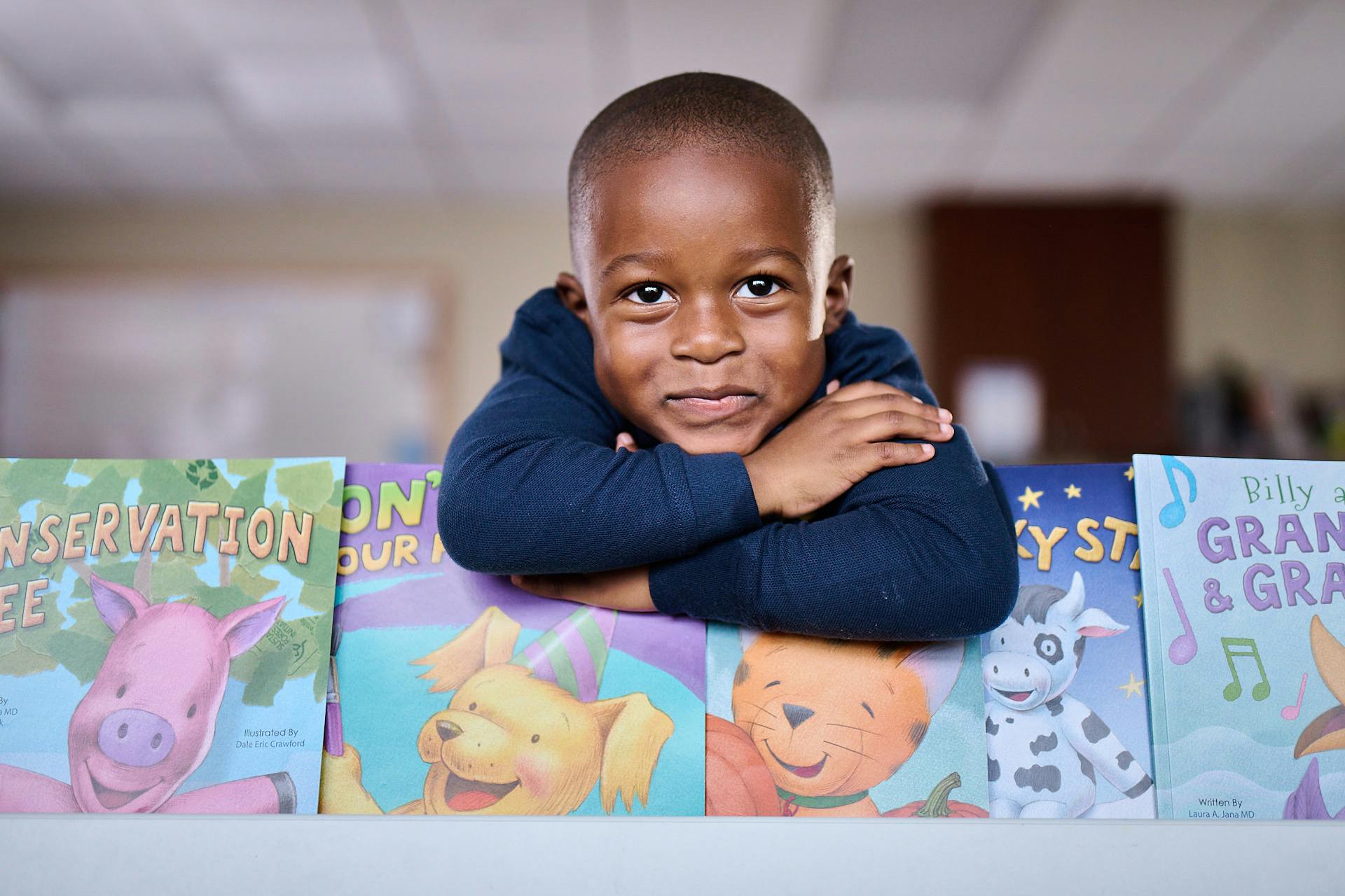 Child resting arms on a row of colorful children's books