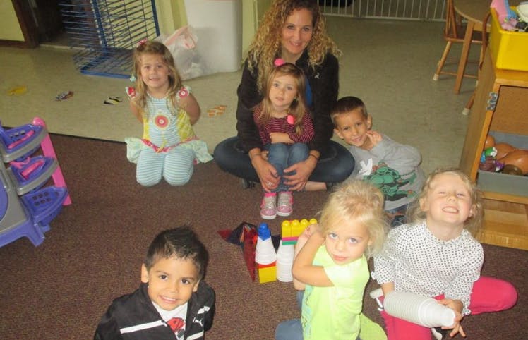 Adult and multiple children sitting on a floor