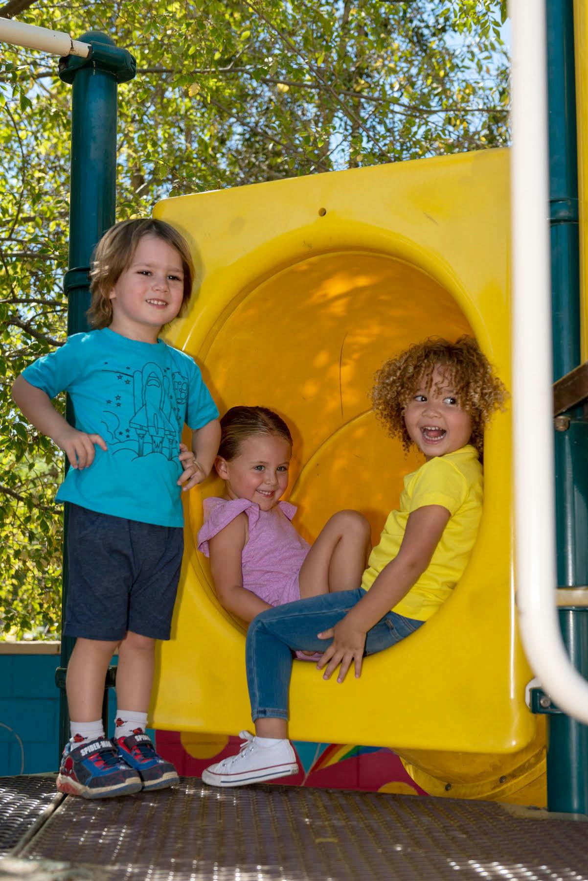 Three children on a playground slide structure