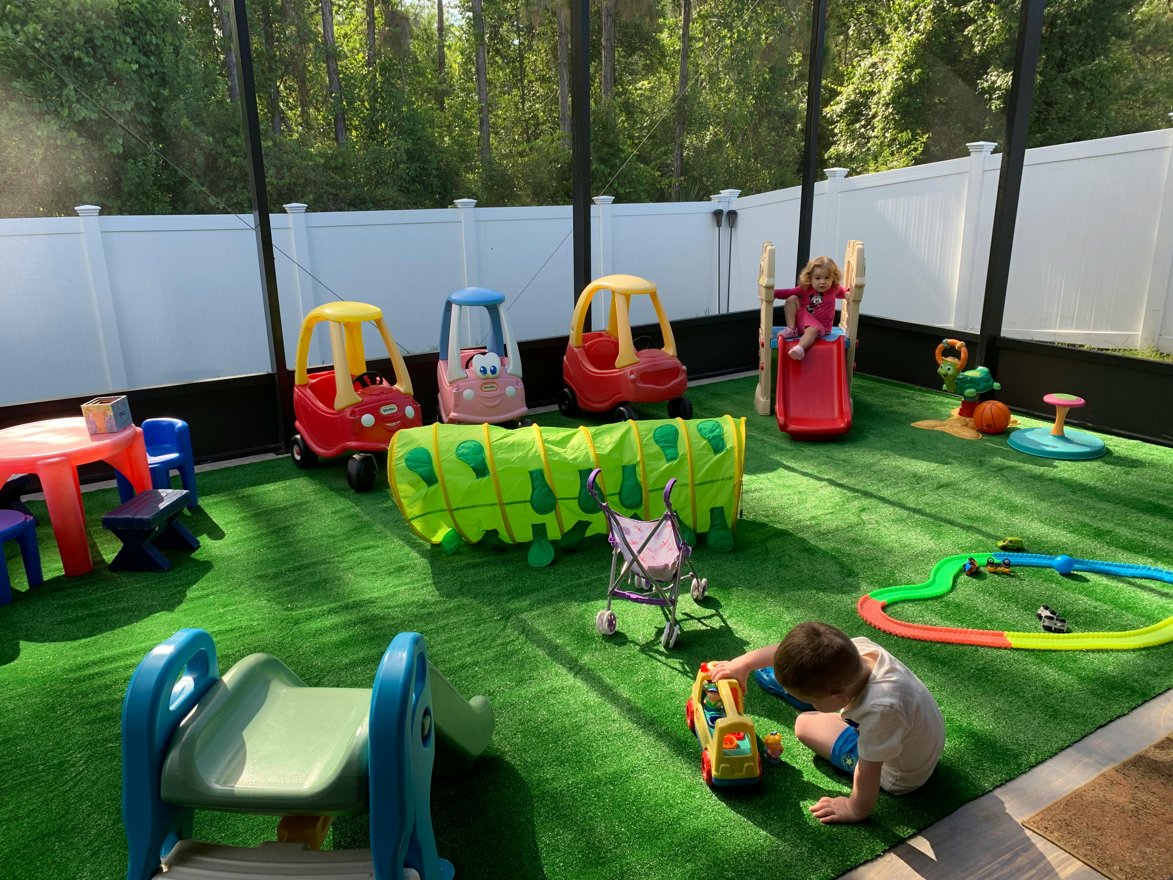 Child playing with toys on artificial grass in an outdoor play area
