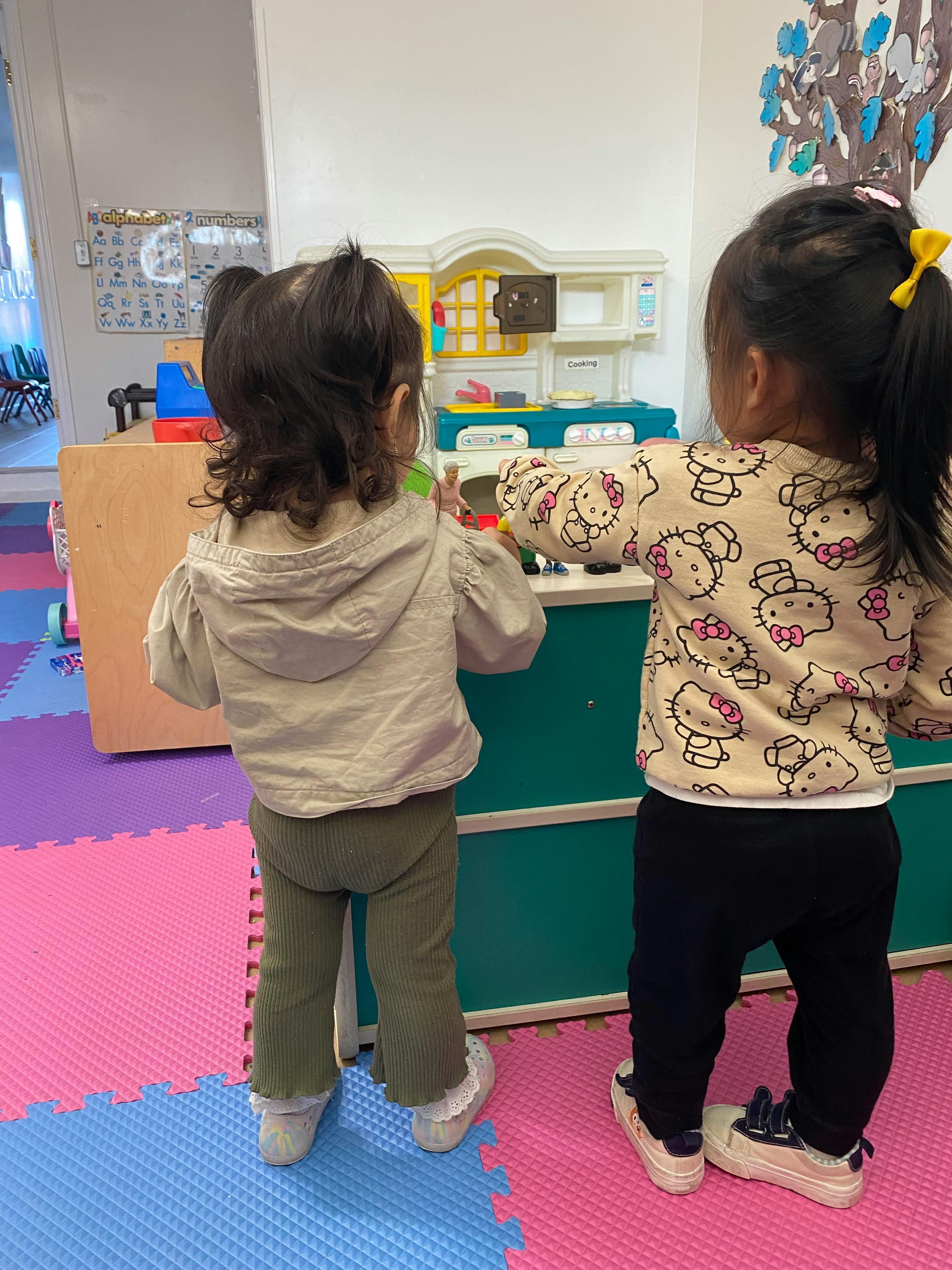 Two children playing with a toy kitchen set