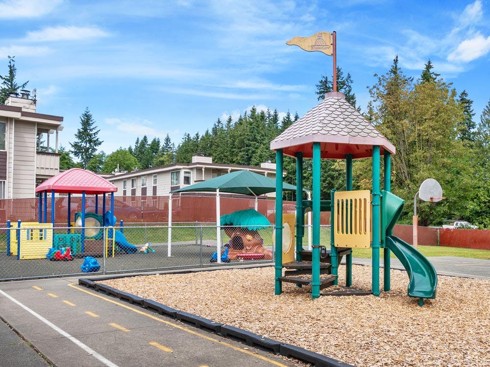 Outdoor playground with multiple colorful play structures and wood chips