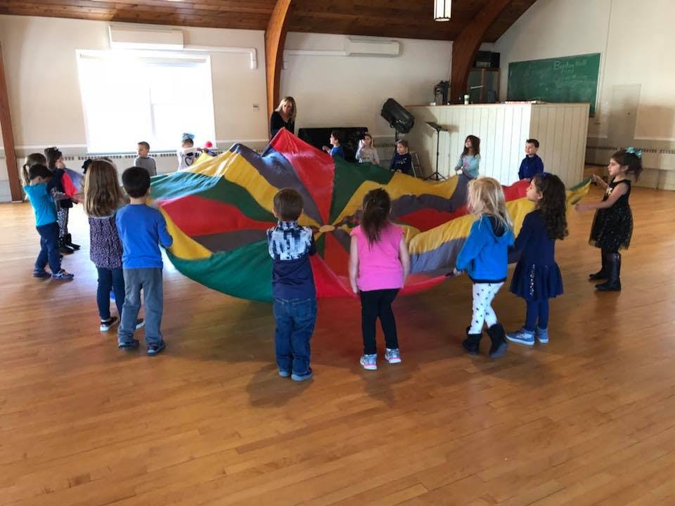 Children playing with a colorful parachute indoors