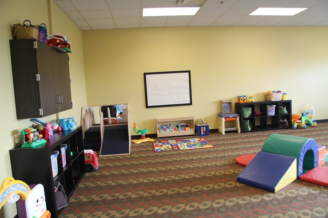 Playroom with soft play equipment, shelves of toys, and a whiteboard