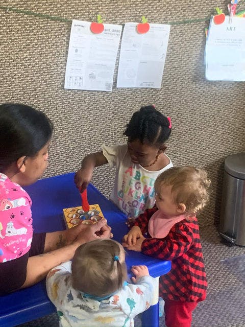 Adult and three children playing a game at a blue table