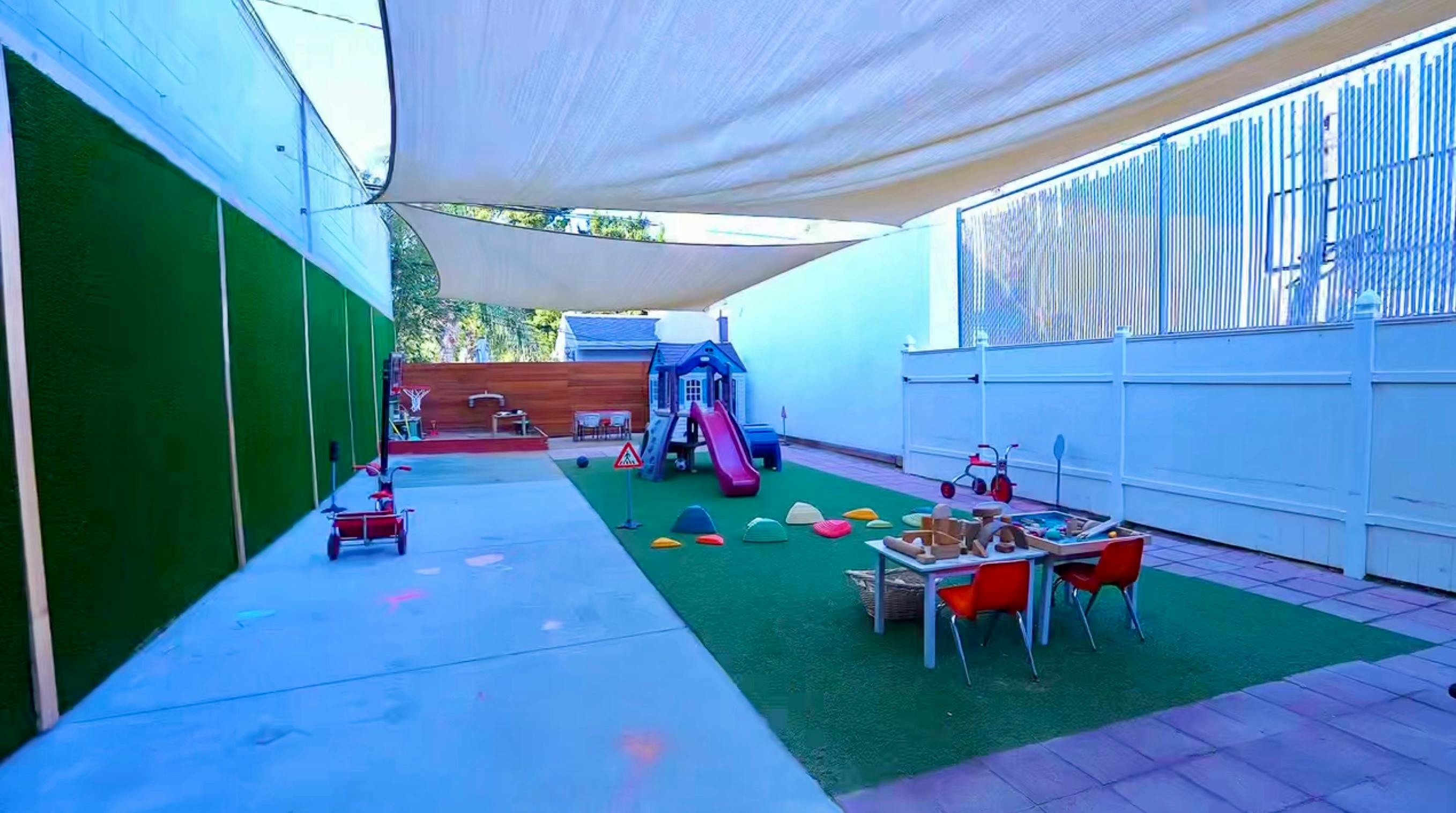 Outdoor children's playground with a slide and play equipment under a canopy