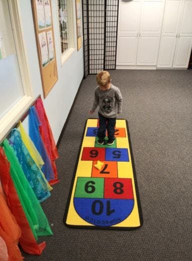 Child standing on a hopscotch mat