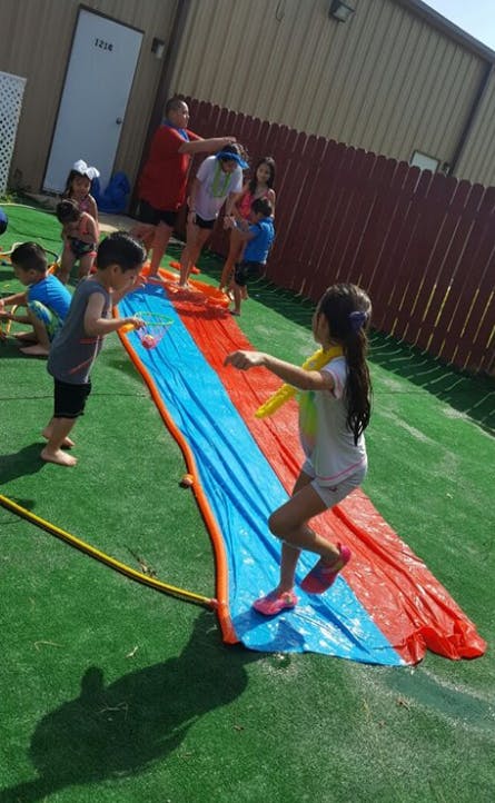 Children playing on a red and blue slip and slide outdoors