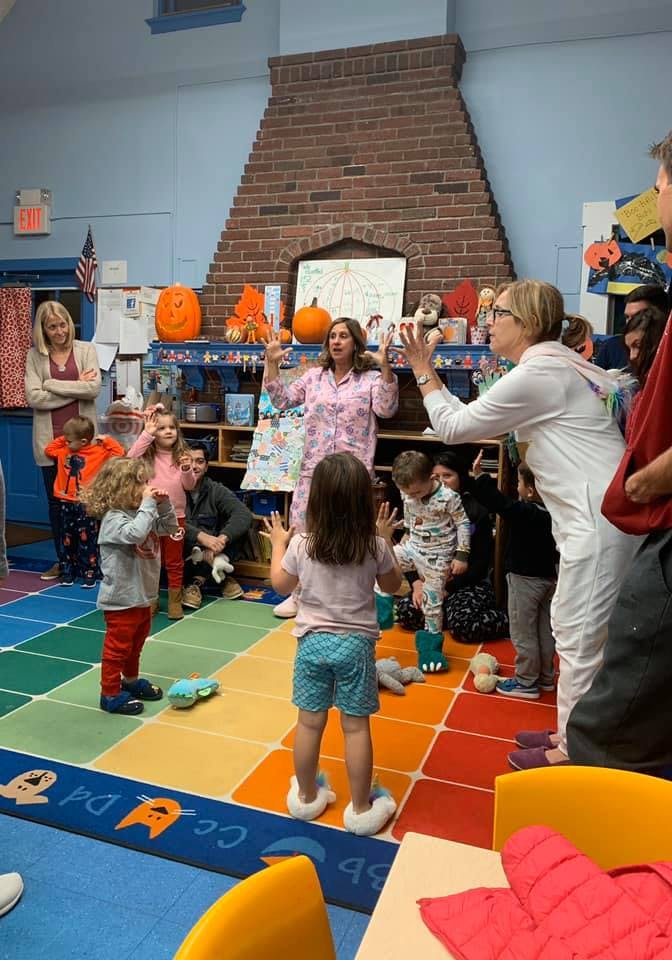 Adults and children in a classroom with adults leading an activity