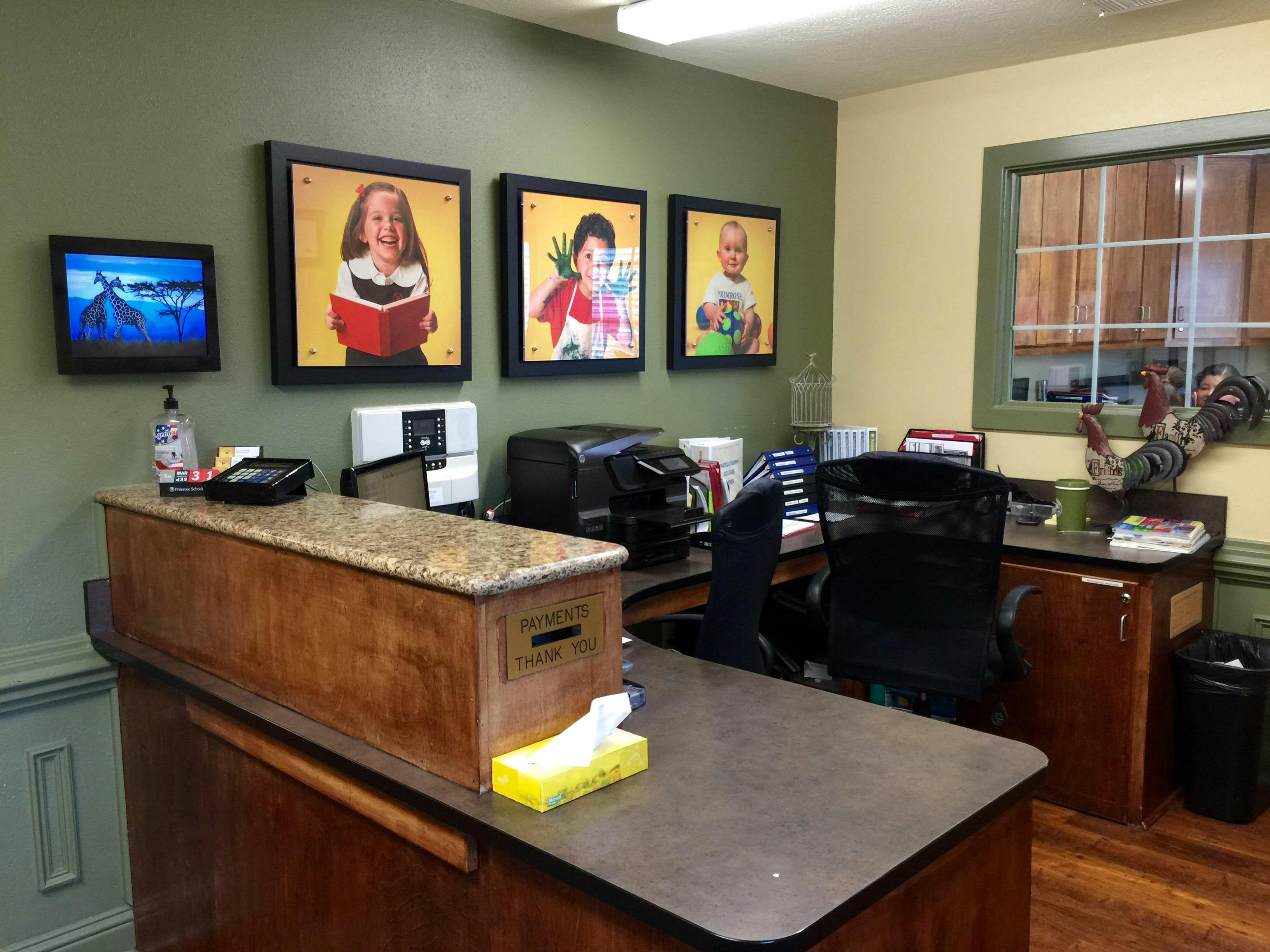 Reception desk with framed photos of children on the wall